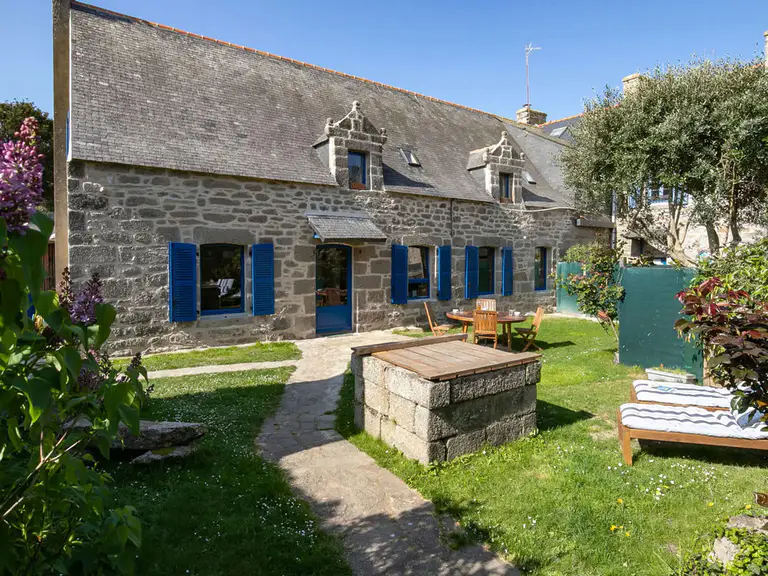 Maison en pierre volets bleus jardin avec 2 transats et un puits